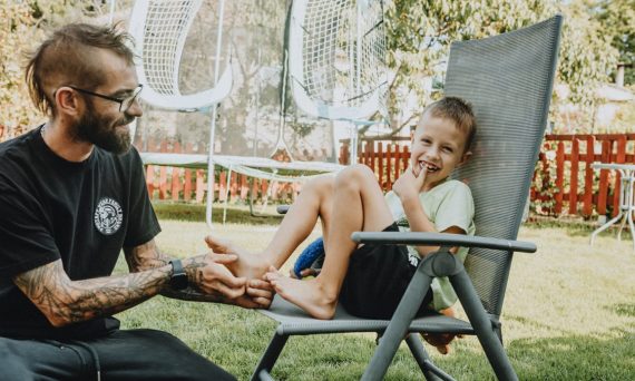 Playful interaction between a father and son in a sunny backyard setting.